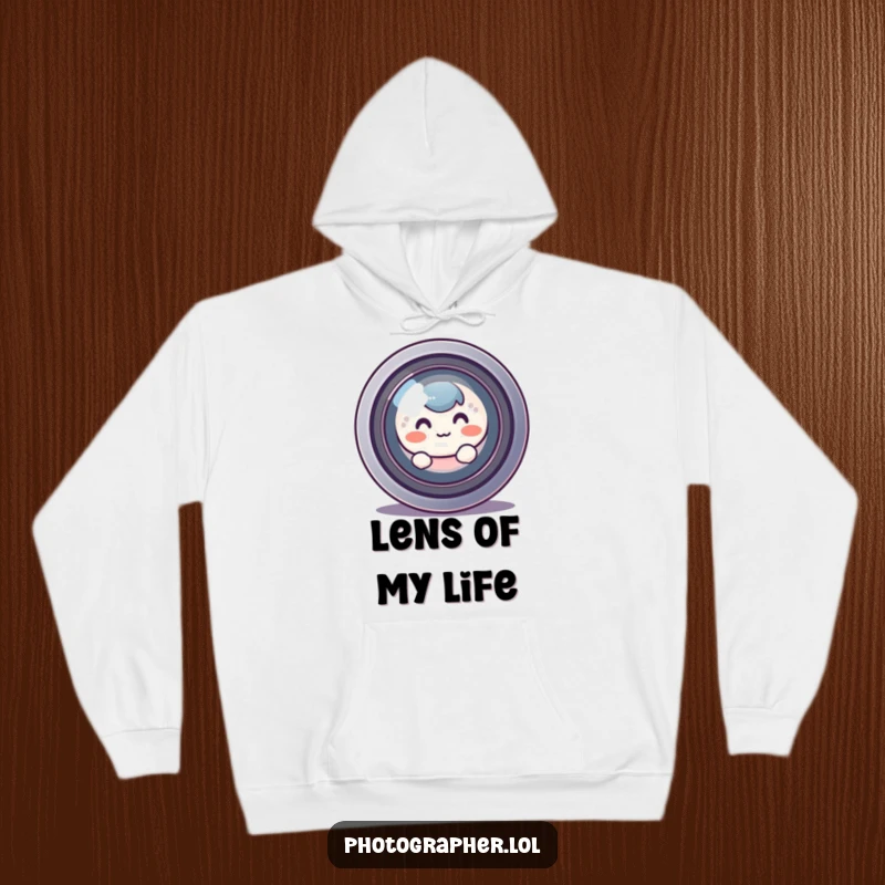 Funny, round character blushing and hiding behind a large camera lens, a cozy and humorous hoodie for shy creatives.